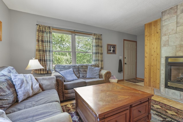 living room with hardwood / wood-style floors, a textured ceiling, and a tiled fireplace