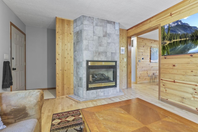 living room featuring a fireplace, a textured ceiling, hardwood / wood-style flooring, and wooden walls