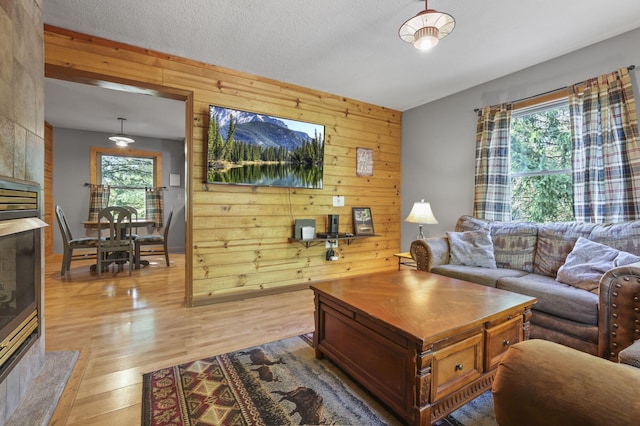 living room featuring plenty of natural light, wood walls, a textured ceiling, and light hardwood / wood-style flooring