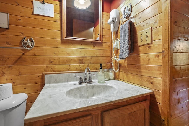 bathroom featuring vanity, toilet, and wooden walls