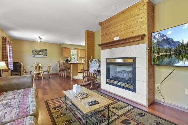 living room featuring a tile fireplace, dark hardwood / wood-style flooring, and sink