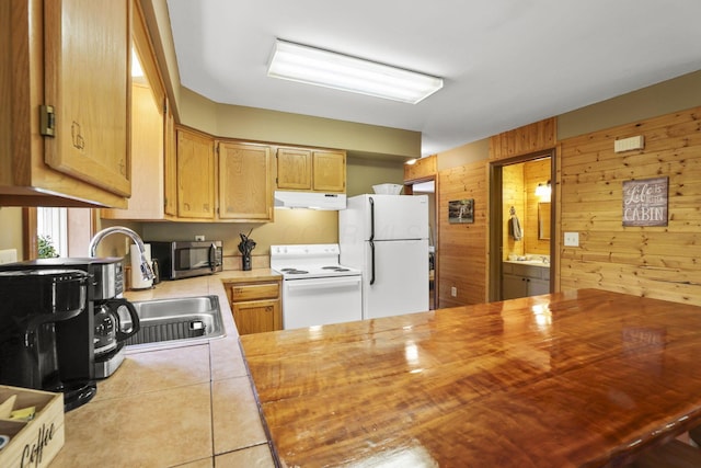 kitchen with kitchen peninsula, wooden walls, light tile patterned floors, and white appliances