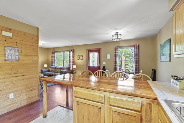 kitchen featuring light brown cabinetry, light hardwood / wood-style floors, and wood walls