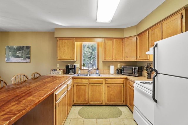 kitchen with light tile patterned floors, white appliances, range hood, and sink