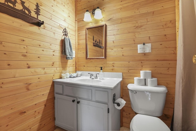 bathroom with vanity, wood walls, and toilet