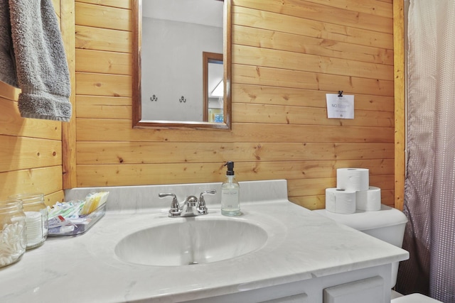 bathroom with sink, toilet, walk in shower, and wood walls