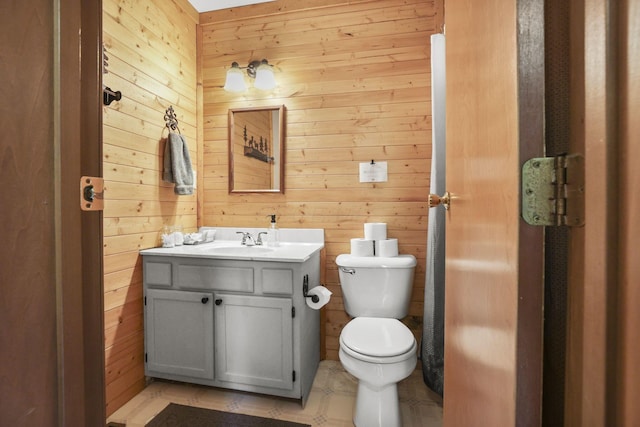 bathroom with vanity, toilet, and wooden walls