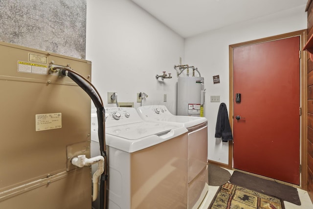 clothes washing area featuring electric water heater and washer and clothes dryer