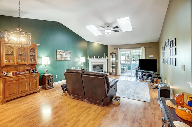 living room with ceiling fan, light wood-type flooring, and lofted ceiling with skylight