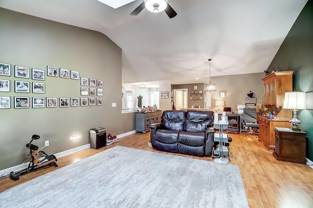 living room featuring ceiling fan with notable chandelier, light hardwood / wood-style flooring, and lofted ceiling