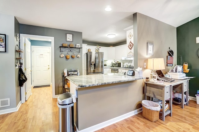 kitchen featuring white cabinetry, light stone countertops, kitchen peninsula, appliances with stainless steel finishes, and light wood-type flooring