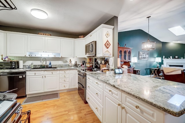 kitchen featuring appliances with stainless steel finishes, sink, light hardwood / wood-style floors, white cabinetry, and hanging light fixtures