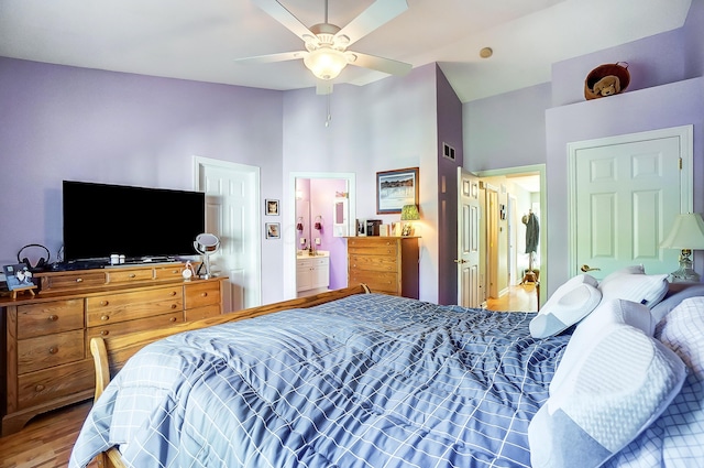 bedroom with ensuite bath, ceiling fan, hardwood / wood-style floors, and a high ceiling