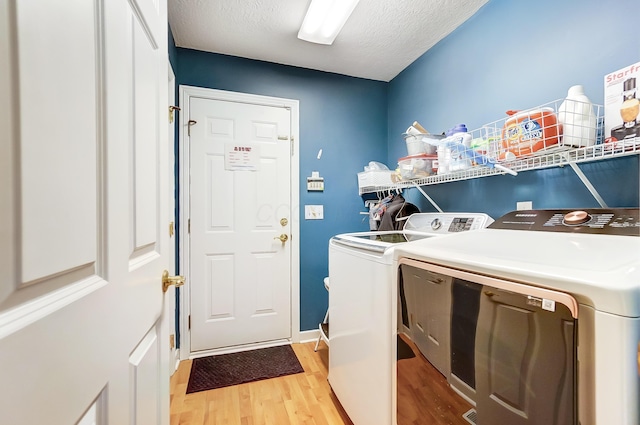 clothes washing area with a textured ceiling, light hardwood / wood-style floors, and washing machine and clothes dryer