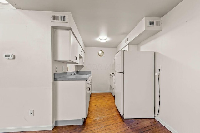 kitchen with white cabinetry, sink, wood-type flooring, and white appliances