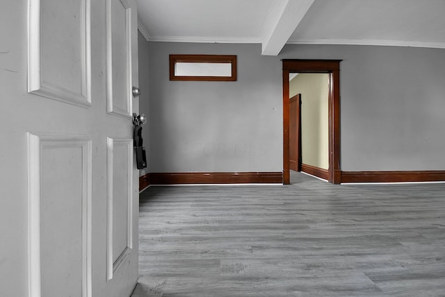 unfurnished room featuring beamed ceiling, light wood-type flooring, and crown molding