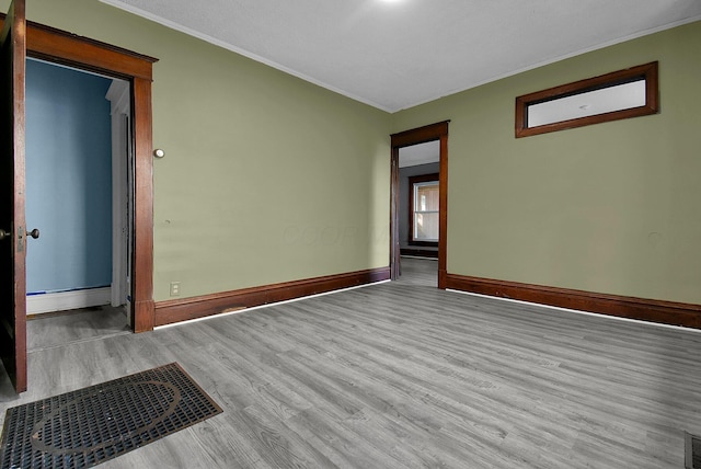 unfurnished room with light hardwood / wood-style floors and crown molding