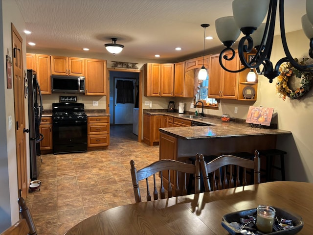 kitchen with sink, kitchen peninsula, a textured ceiling, decorative light fixtures, and black appliances