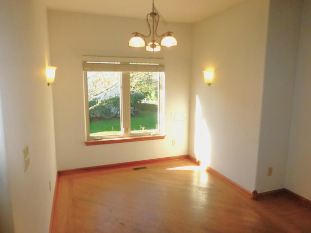 unfurnished room featuring hardwood / wood-style flooring and a notable chandelier