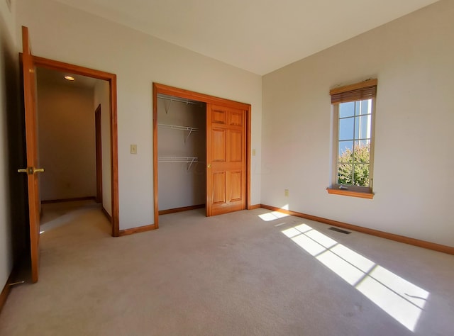 unfurnished bedroom featuring light colored carpet and a closet