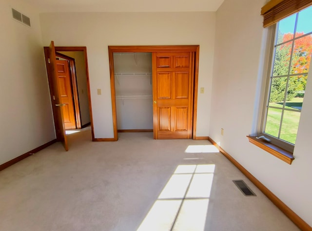 unfurnished bedroom with a closet, light colored carpet, and multiple windows