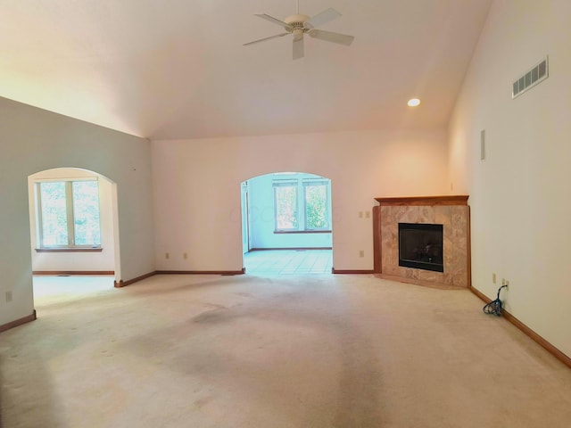 unfurnished living room featuring plenty of natural light, ceiling fan, light carpet, and a high end fireplace