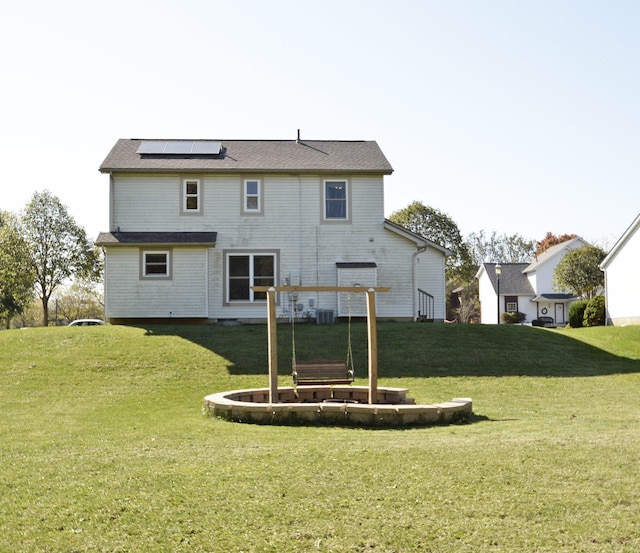 back of property featuring solar panels, cooling unit, and a yard