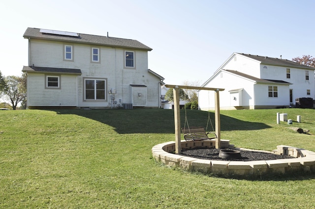 back of house with a yard and solar panels