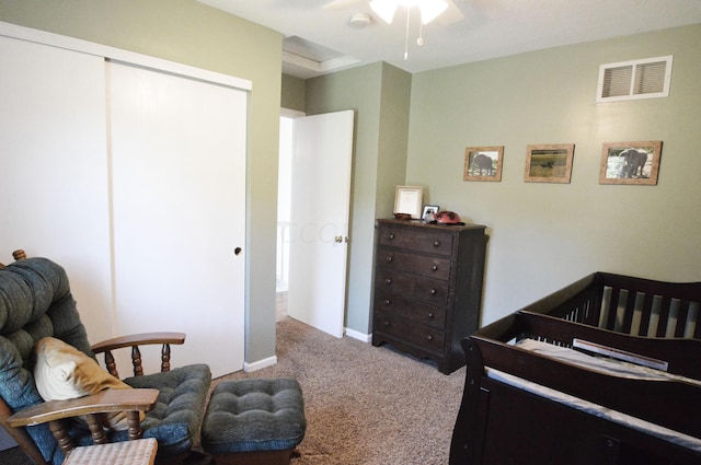 carpeted bedroom with ceiling fan and a nursery area