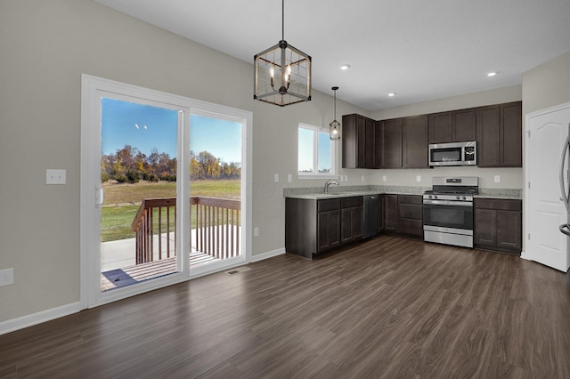 kitchen featuring sink, appliances with stainless steel finishes, decorative light fixtures, dark hardwood / wood-style flooring, and dark brown cabinetry