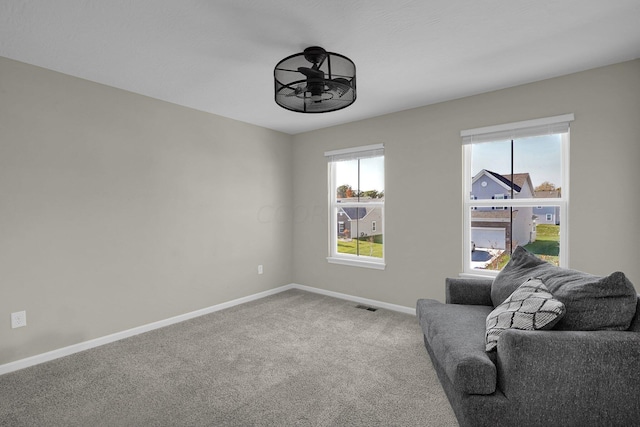 living area with ceiling fan, plenty of natural light, and carpet