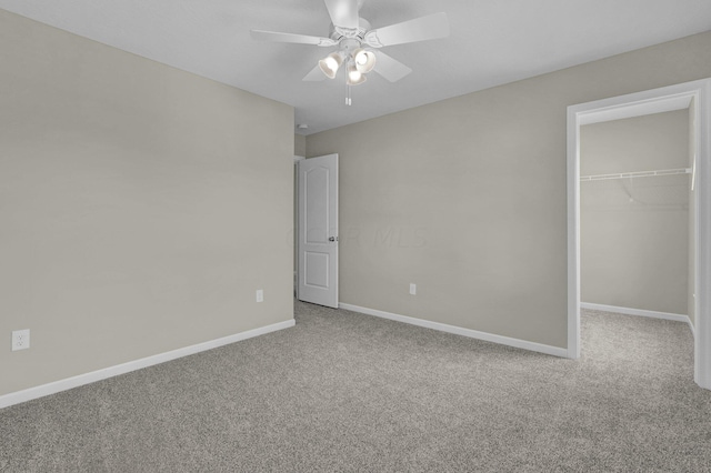 unfurnished bedroom featuring ceiling fan, a walk in closet, carpet floors, and a closet