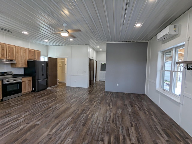 kitchen featuring under cabinet range hood, stainless steel range with electric cooktop, an AC wall unit, freestanding refrigerator, and dark countertops