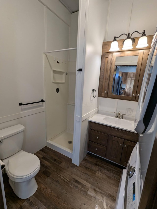 bathroom with toilet, a stall shower, wood finished floors, and vanity