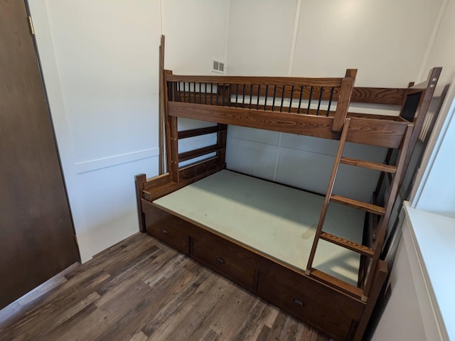 bedroom with dark wood-style floors and visible vents