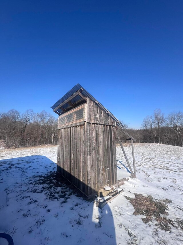 snow covered structure with an outbuilding