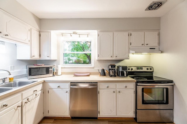 kitchen featuring white cabinets, wood-type flooring, stainless steel appliances, and sink