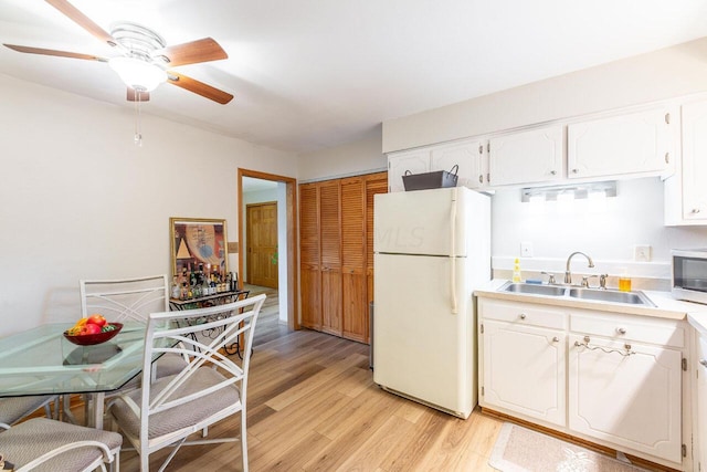 kitchen with white refrigerator, sink, light hardwood / wood-style flooring, ceiling fan, and white cabinetry