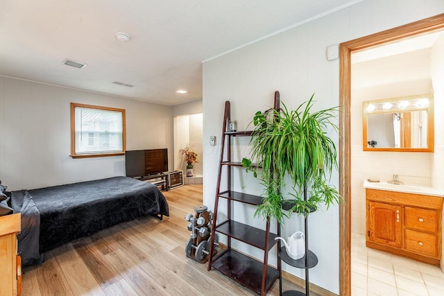 bedroom featuring ensuite bath, light hardwood / wood-style flooring, and sink