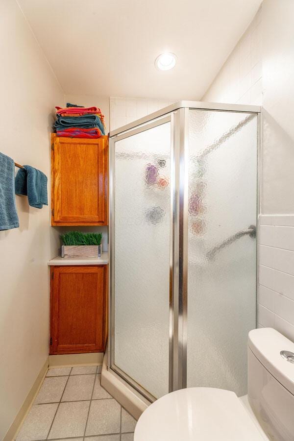 bathroom featuring toilet, tile patterned flooring, and walk in shower