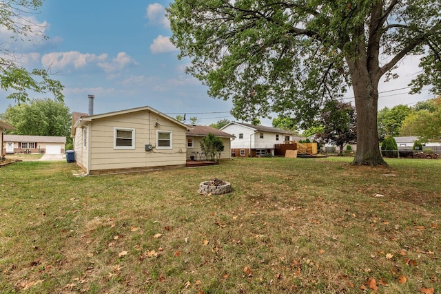 rear view of house with a lawn and an outdoor fire pit