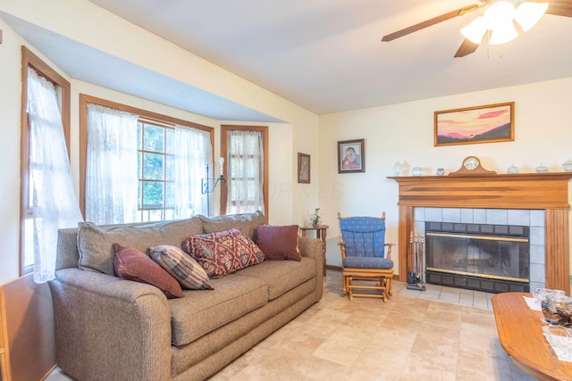 living room with a tile fireplace and ceiling fan