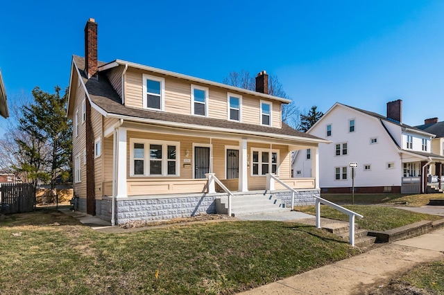 view of front facade featuring a porch, fence, a front yard, a shingled roof, and a chimney