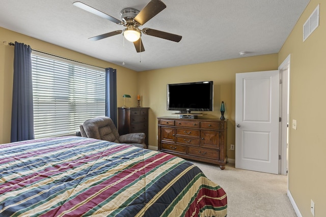 carpeted bedroom featuring ceiling fan and a textured ceiling