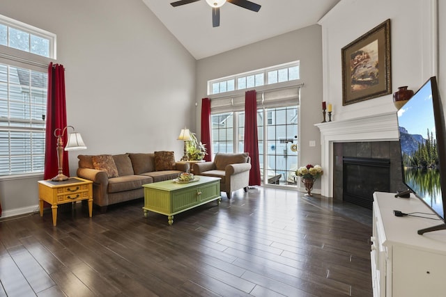 living room with a tile fireplace, dark wood-type flooring, and a healthy amount of sunlight