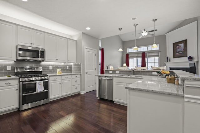 kitchen with sink, dark wood-type flooring, decorative light fixtures, white cabinets, and appliances with stainless steel finishes