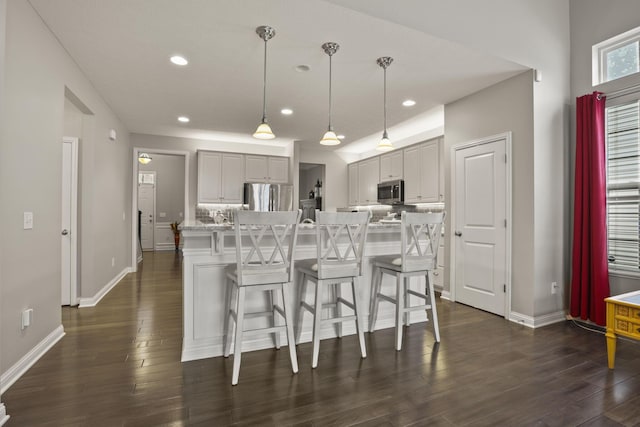 kitchen with a kitchen breakfast bar, an island with sink, decorative light fixtures, and appliances with stainless steel finishes