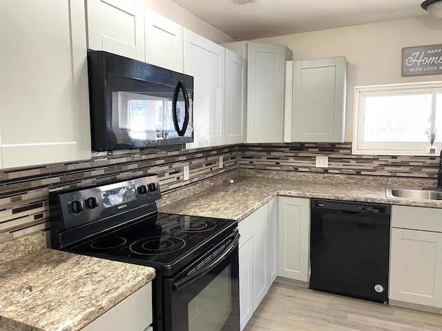 kitchen with black appliances, sink, tasteful backsplash, and white cabinetry