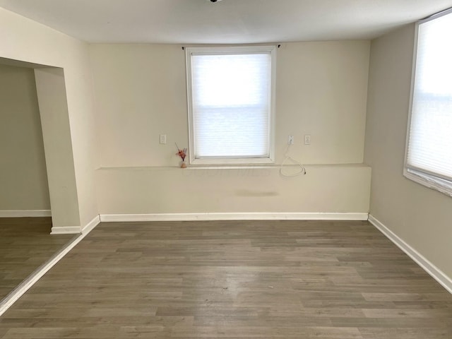 empty room with dark wood-type flooring and plenty of natural light