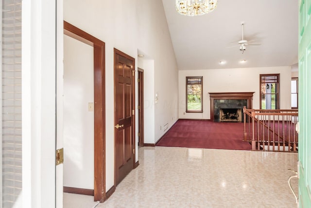 hall with a wealth of natural light, vaulted ceiling, and a notable chandelier